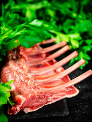 Fresh raw rack of lamb on a stone board with parsley. 