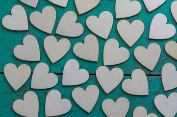 Love Valentines day background, group of light wooden hearts spread on vintage blue green scratched table, flat lay one by one