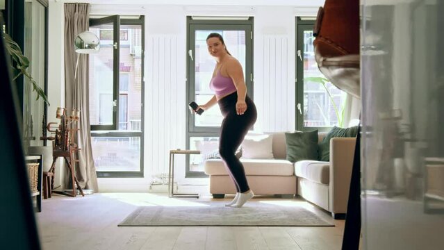 Active body positive woman dancing and listening music at home