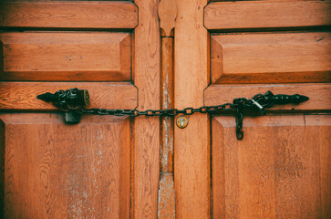 Close up view of a brown wooden old door and door handle with chain