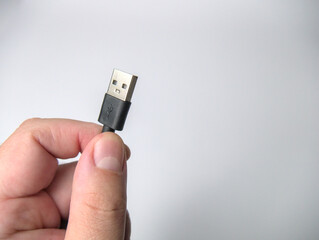 A man's hand holding unplugged USB cable, isolated on a white background