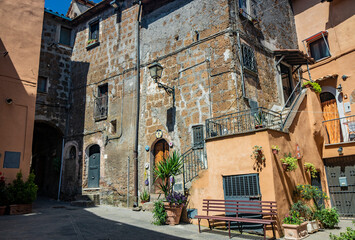June 02, 2022 - Corchiano, Viterbo, Lazio - Small medieval village. The narrow streets of the small town with the old brick houses. The blue sky on a sunny day in summer.
