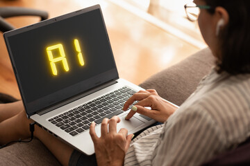 Artificial intelligence word on the screen of a laptop. Woman typing on the keyboard working home office.