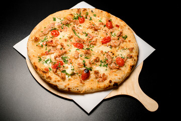 view on pizza with cherry tomatoes and chicken garnished by green