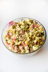 New Year's salad of meat vegetables and mayonnaise in a large plate. Delicious salad with corn and potatoes.