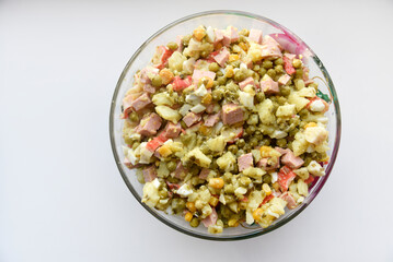 New Year's salad of meat vegetables and mayonnaise in a large plate. Delicious salad with corn and potatoes.