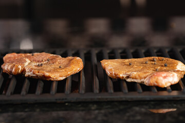 meat steaks sprinkled with pepper are fried on a grill