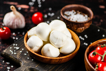 Mozzarella cheese on a cutting board with spices and tomatoes. 