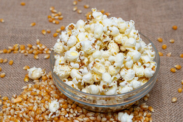 Popcorn in glass bowl on rustic burlap table with seed corn