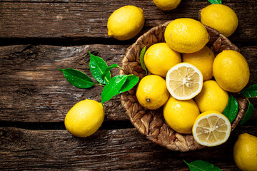 Halves and whole lemons with leaves in a basket. 