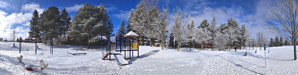 Panoramic photo of the slide - Kids' play area equipment covered with snow in the public park. Web banner
