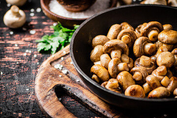 Frying pan with fried small mushrooms with parsley. 