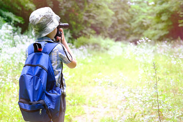 child of 7-8 years, boy in Panama hat, plaid shirt with walkie-talkie in hand stands in forest,...