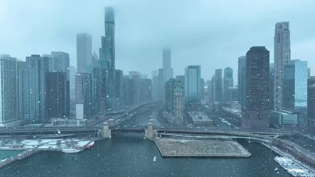 Drone aerial view panning across Chicago downtown skyline of buildings, flying over Lake Michigan, snowing in winter on cloudy day