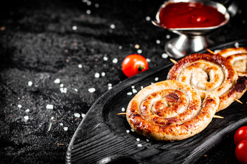 Round grilled sausages on a tray with tomato sauce.