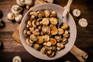 Fried mushrooms in a bowl on a cutting board. 