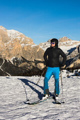  A young man, a happy skier, admires the Italian Dolomites mountains. Skiing, winter sports. Młody mężczyzna, szczęśliwy narciarz podziwia włoskie góry Dolomity. Narty, sporty zimowe. - obrazy, fototapety, plakaty