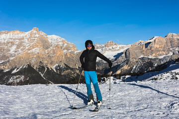  A young man, a happy skier, admires the Italian Dolomites mountains. Skiing, winter sports. ...