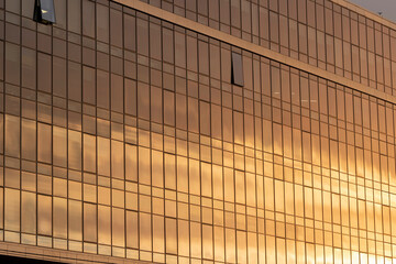 Modern office building facade. Tall business center with a glass facade. Construction of a glass facade structure. The glare of the sun on the glass wall of a skyscraper