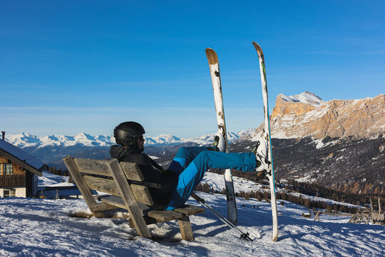 Skier resting on a bench overlooking the Italian Dolomites mountains. Ski, winter sport. Narciarz odpoczywa na ławce i podziwia włoskie g&oacute;ry Dolomity. Narty, sporty zimowe. Pralongia.
