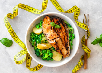 Dinner plate with fresh salmon grilled steak with vegetables and measuring tape top view. Diet, dietary food concept