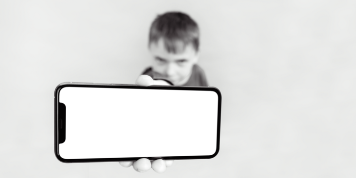 The child holds the phone in his hand for advertising on a yellow background. Color