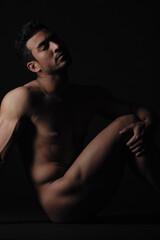 Obraz na płótnie Canvas Nude, art and freedom with a model asian man in studio on a dark background for artistic body positivity. Skin, natural and artwork with a handsome young male posing naked on a black backdrop