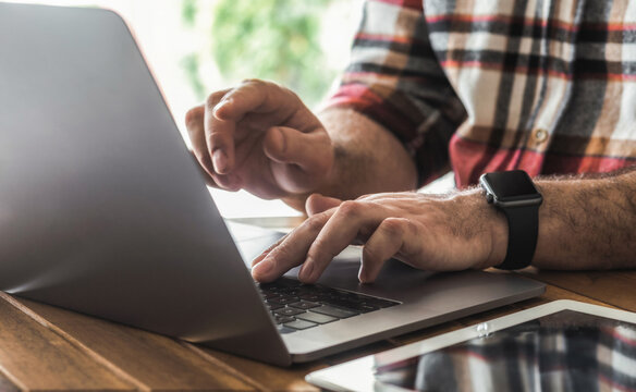 Male freelancer or entrepreneur using laptop working from home or coworking. Remote online work, safe internet banking concept