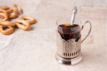 a glass of tea in a metal cup holder, bagels in the background