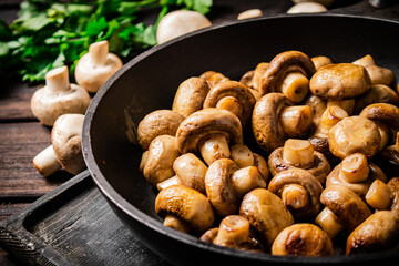 Fragrant homemade fried mushrooms in a frying pan on a cutting board. 