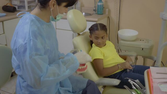 Video Of A Transgender Doctor Of Dentistry In Her Medical Office Explaining To Her Little Patient How To Brush Her Teeth Properly With A Dental Dummy In Her Hand.