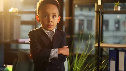 Portrait of cute energetic successful little businessman child kid looking at the camera with crossed arms in the modern office workplace Ambitious young people or early start of business concept
