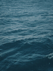 Dense surface of the water element of a deep, unusually beautiful color of the blue spectrum. Active movement of water creates relief with small waves on the surface. Sunlight reflects off the water.