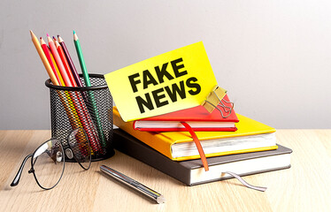 FAKE NEWS written on a sticky on notebooks