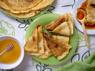 Homemade thin fried pancakes stacked in a plate, served with honey. Maslenitsa holiday. Delicious breakfast or snack.