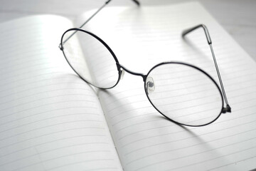 notepad, eyeglass and a pencil on wooden table 