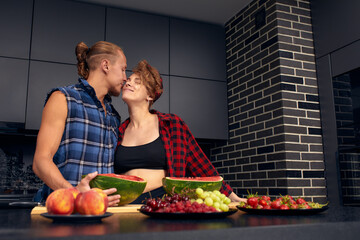 A young couple of spouses in the kitchen in their new apartment drinking coffee, eating fruit, cooking