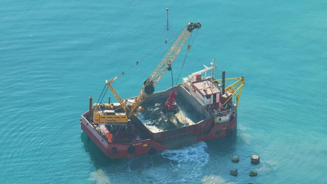A boat is dredging the sea. Dredging is the removal of sediments and debris from the bottom of lakes, rivers, harbors, and other water bodies.
