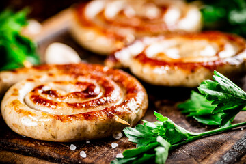 Grilled sausages with parsley on a wooden background.