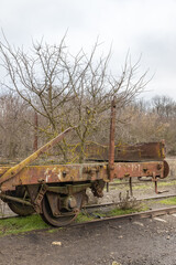 Old rusty industrial freight wagon in an abandoned train station. Train car claimed by nature.