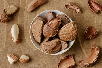 Unshelled and shelled Brazil nuts on brown wooden table. Top view.