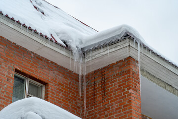 Icicles onroof of private house resulting from improper construction of roof. Metal Downpipe system, Guttering System, External downpipes and drainage pipes at winter