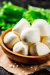 Mozzarella cheese in a wooden plate with lettuce. 