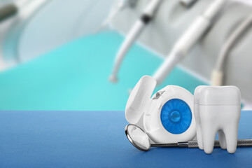Plastic tooth with dental floss and tool on table in clinic