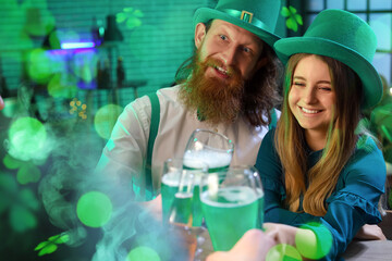 Happy young couple with glasses of beer and their friends celebrating on St. Patrick's Day in pub