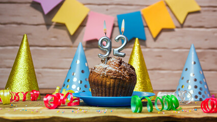 Festive cake with a candle with a number  92. Happy birthday background with beautiful decorations.Anniversary party copy space.