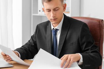 Handsome businessman working with papers at desk in office