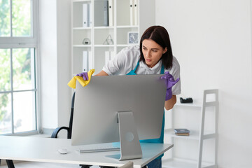 Female janitor wiping computer in office