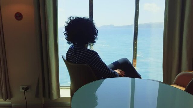 Commuter woman enjoy sea view from cruising ferry boat panoramic window
