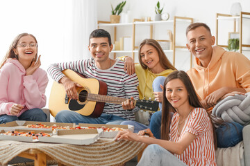 Young man playing guitar for his friends in living room